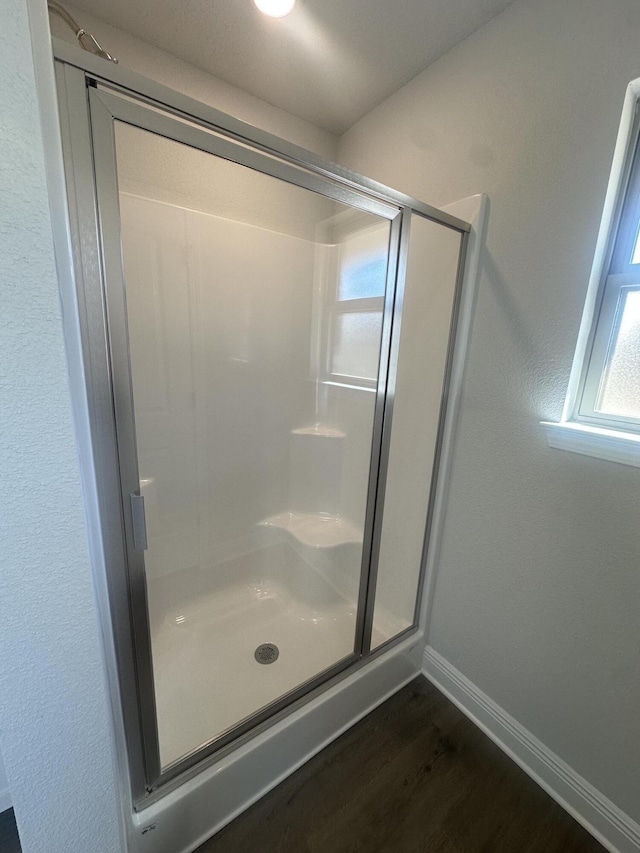 bathroom featuring a shower stall, baseboards, and wood finished floors