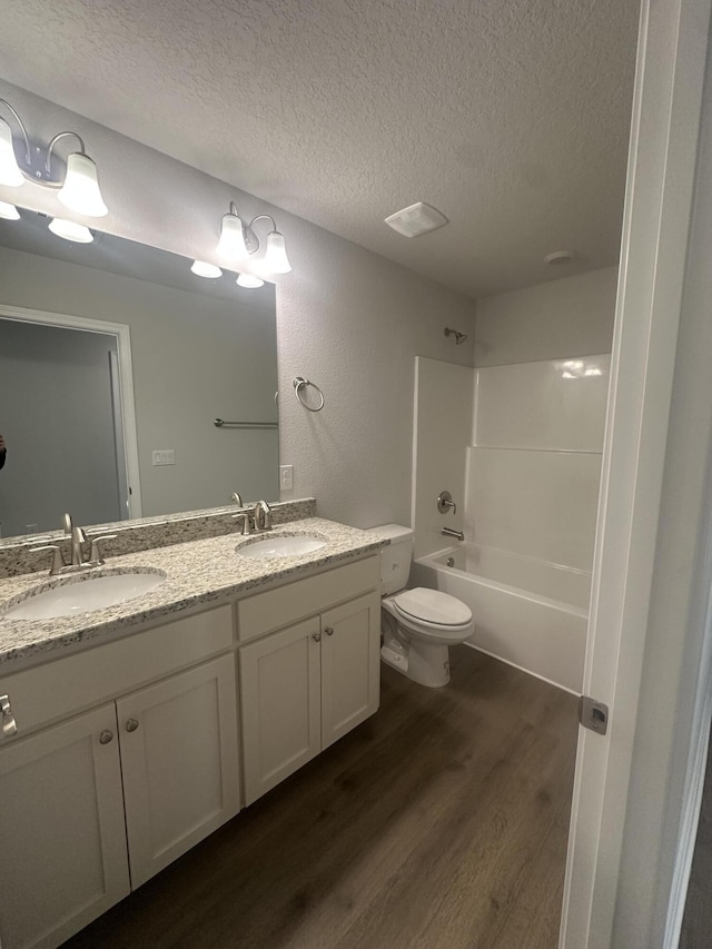 bathroom featuring double vanity, a sink, a textured ceiling, and wood finished floors