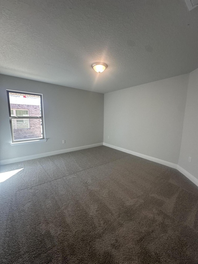 spare room with visible vents, carpet flooring, a textured ceiling, and baseboards