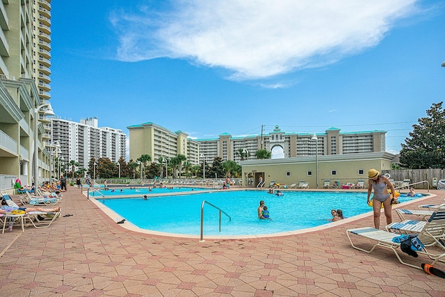 community pool with a view of city, fence, and a patio