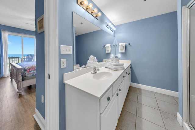 ensuite bathroom with tile patterned flooring, connected bathroom, vanity, and baseboards