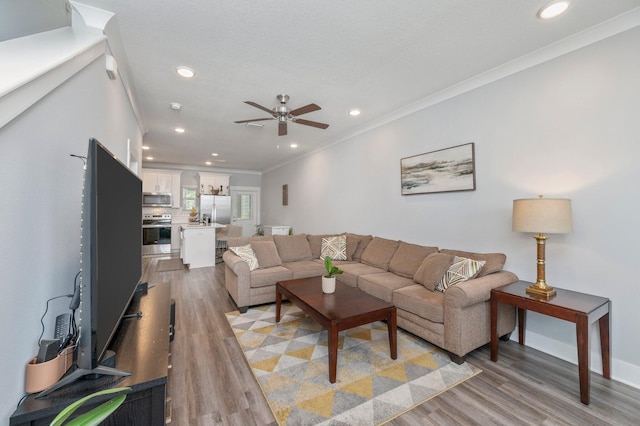 living room with crown molding, light wood-type flooring, and ceiling fan