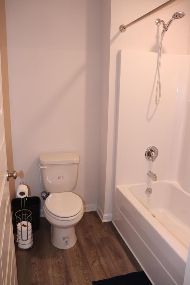 bathroom featuring hardwood / wood-style floors, bathing tub / shower combination, and toilet