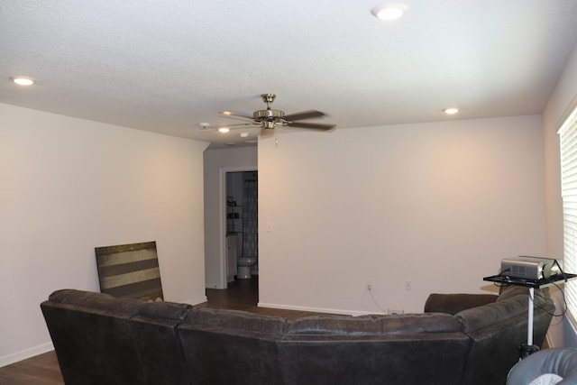 living room featuring a textured ceiling, ceiling fan, and dark hardwood / wood-style floors