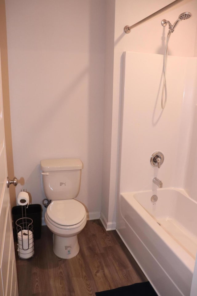 bathroom with bathing tub / shower combination, toilet, and hardwood / wood-style flooring