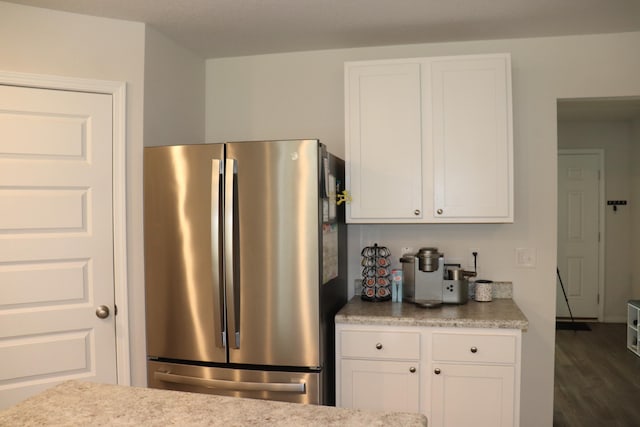 kitchen featuring light stone counters, dark wood-type flooring, white cabinetry, and stainless steel refrigerator