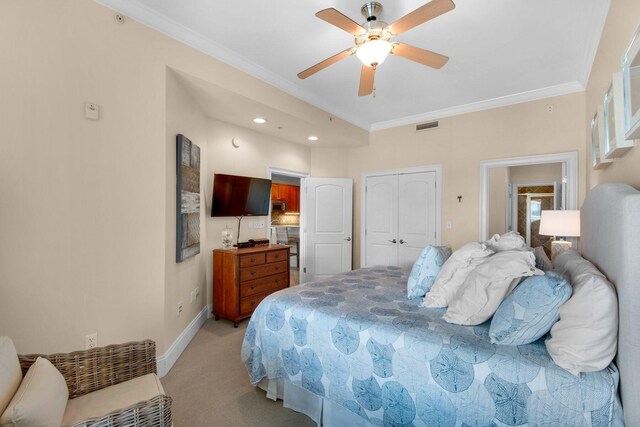 carpeted bedroom with ceiling fan, a closet, and crown molding