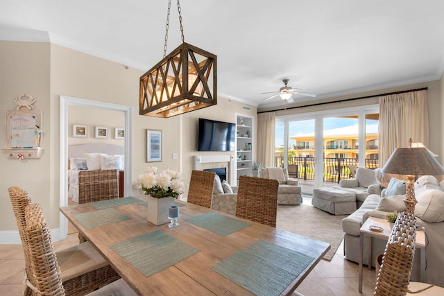 dining area featuring light tile patterned floors, crown molding, ceiling fan, and built in shelves