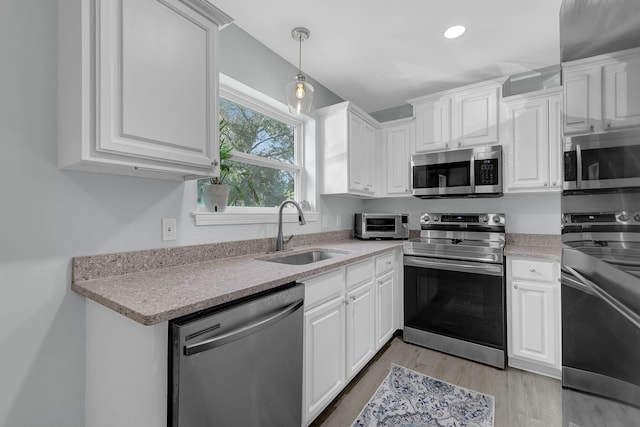 kitchen featuring appliances with stainless steel finishes, sink, white cabinets, and light hardwood / wood-style floors