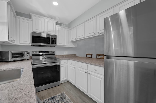 kitchen with light wood-type flooring, white cabinets, appliances with stainless steel finishes, and sink