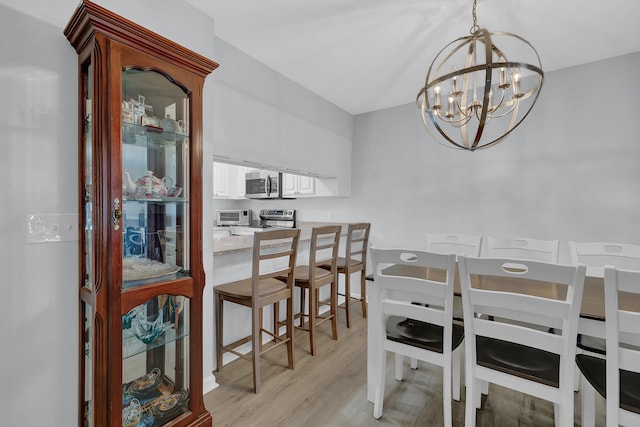 dining room with light wood-type flooring and a chandelier