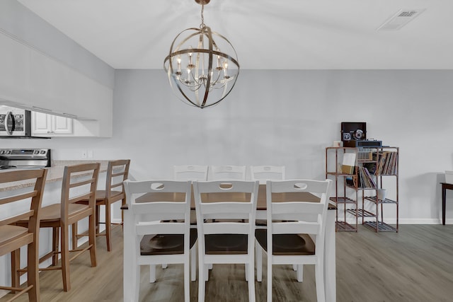 dining space featuring light hardwood / wood-style flooring and a notable chandelier