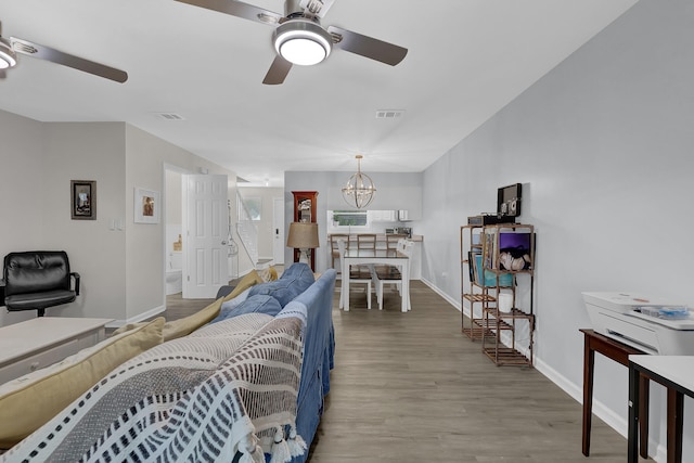 living room featuring ceiling fan with notable chandelier and wood-type flooring