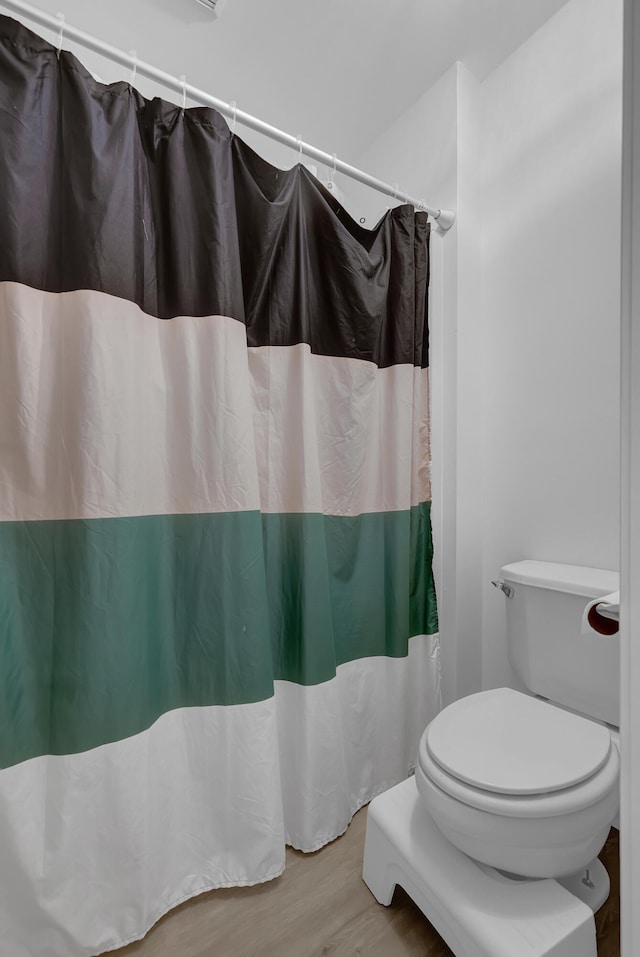 bathroom featuring curtained shower, toilet, and hardwood / wood-style flooring