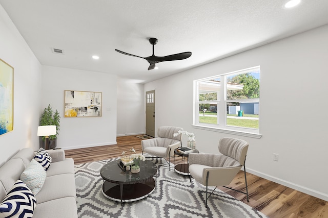 living room with wood-type flooring, ceiling fan, and a textured ceiling