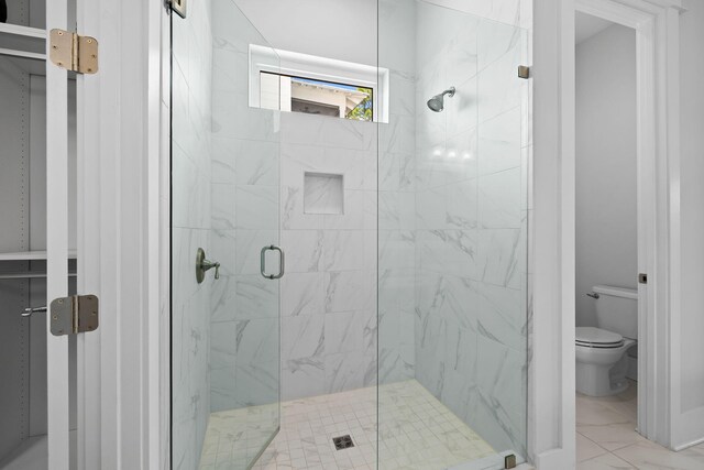 bathroom featuring a shower with shower door, toilet, and tile patterned flooring