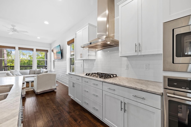 kitchen featuring backsplash, stainless steel appliances, wall chimney exhaust hood, white cabinets, and dark hardwood / wood-style flooring