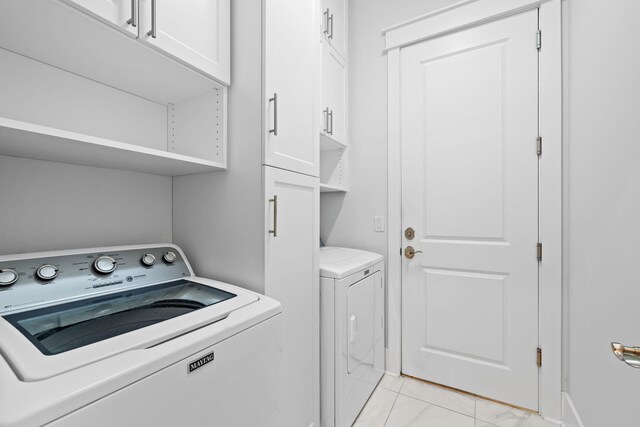 washroom with light tile patterned floors, separate washer and dryer, and cabinets