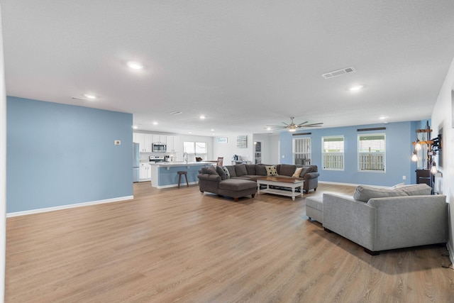 living room featuring light hardwood / wood-style floors, sink, and ceiling fan