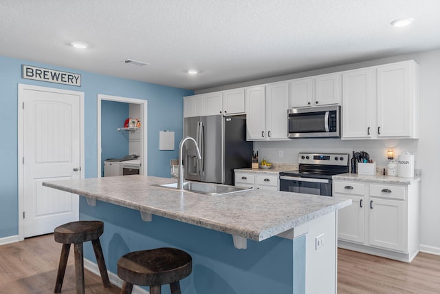 kitchen featuring a breakfast bar, light hardwood / wood-style flooring, a center island with sink, and stainless steel appliances