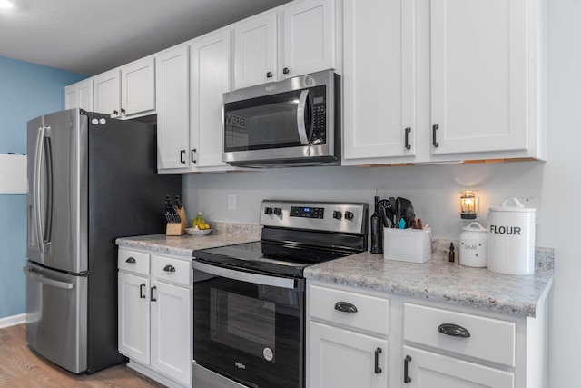 kitchen with stainless steel appliances, light hardwood / wood-style floors, white cabinets, and light stone counters