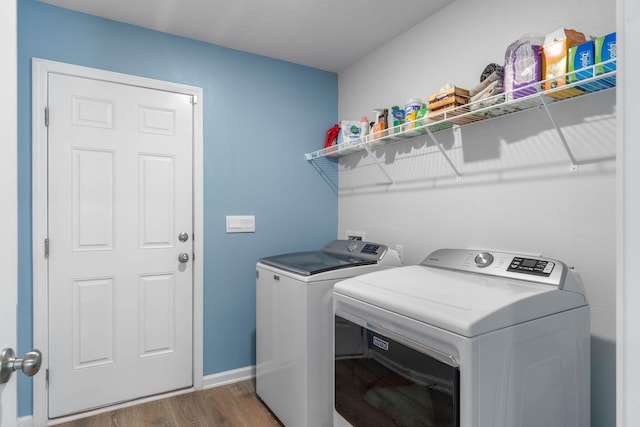 clothes washing area with separate washer and dryer and wood-type flooring