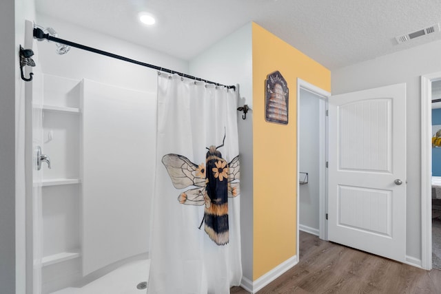 bathroom featuring hardwood / wood-style flooring, a textured ceiling, and walk in shower