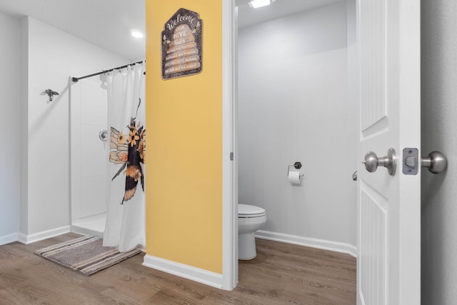 bathroom with hardwood / wood-style flooring, a shower with shower curtain, and toilet