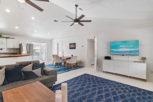 carpeted living room featuring ceiling fan, a textured ceiling, and high vaulted ceiling