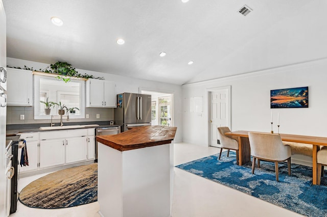 kitchen with lofted ceiling, white cabinets, sink, decorative backsplash, and appliances with stainless steel finishes