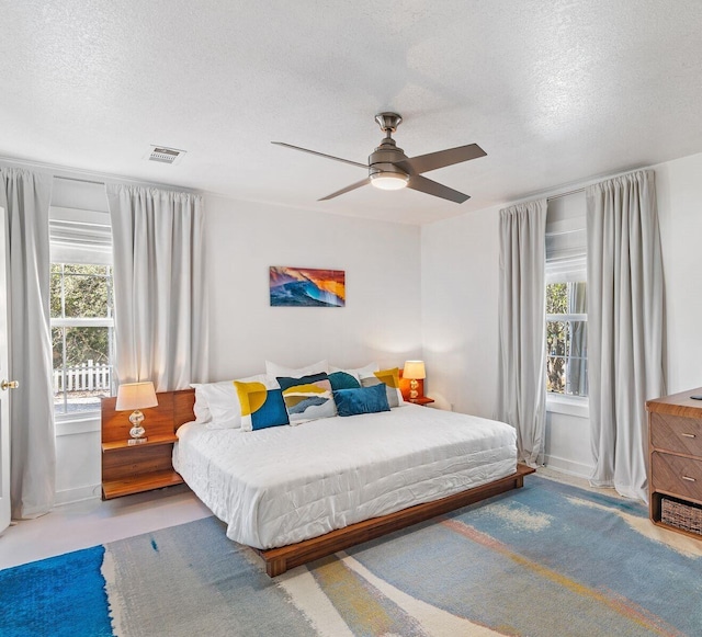 bedroom featuring a textured ceiling, multiple windows, and ceiling fan