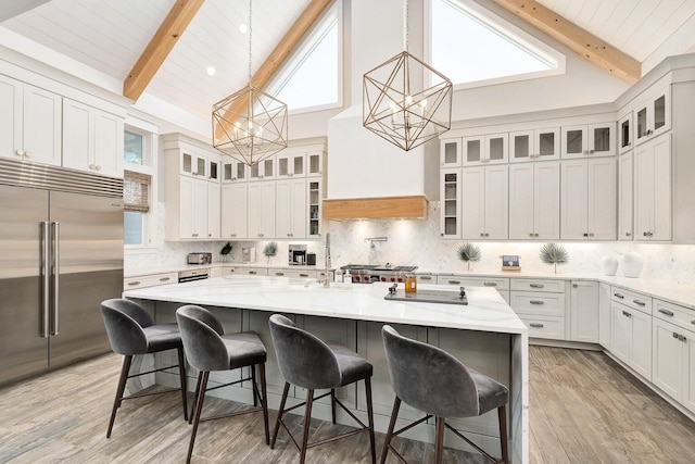 kitchen with a kitchen breakfast bar, stainless steel appliances, beam ceiling, a center island with sink, and a chandelier