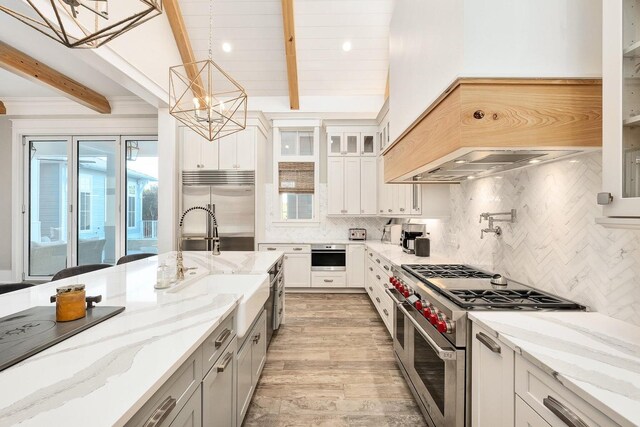 kitchen featuring hanging light fixtures, white cabinets, premium appliances, an inviting chandelier, and sink