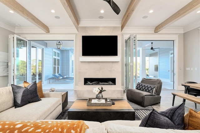 living room with beam ceiling, ceiling fan, hardwood / wood-style flooring, and a tiled fireplace