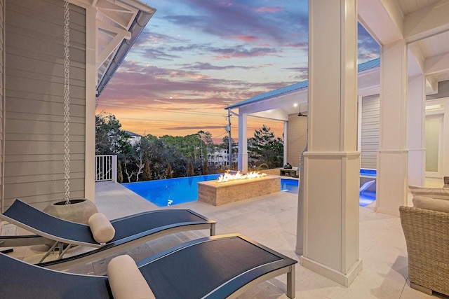 pool at dusk with an outdoor fire pit and a patio area