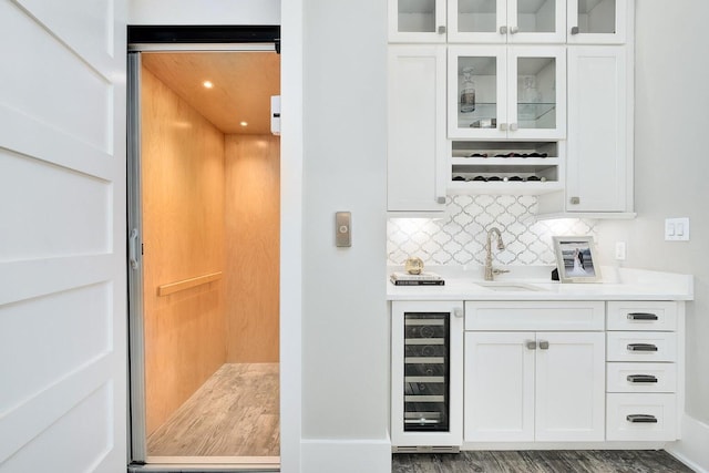 bar with white cabinetry, wine cooler, dark hardwood / wood-style flooring, elevator, and sink