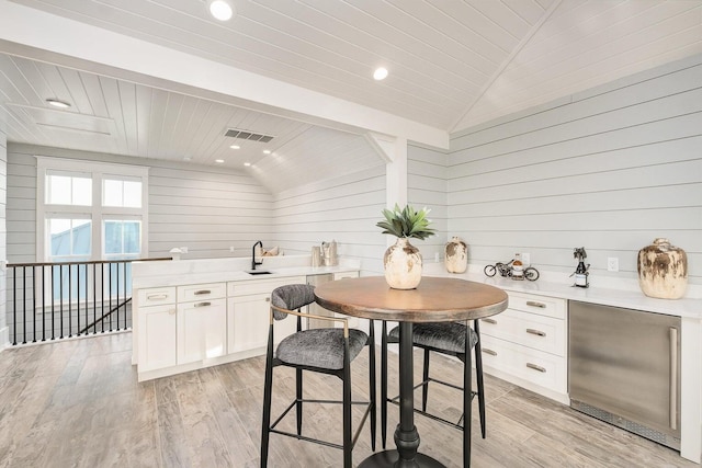 interior space featuring vaulted ceiling with beams, light hardwood / wood-style flooring, wood walls, and wood ceiling