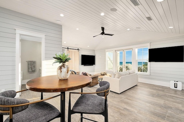 dining room featuring a barn door, vaulted ceiling, light hardwood / wood-style flooring, and wooden ceiling