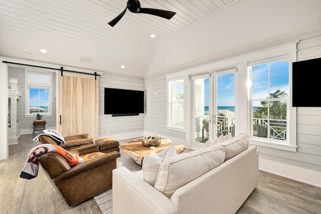 living room featuring vaulted ceiling, a barn door, wooden ceiling, ceiling fan, and hardwood / wood-style floors