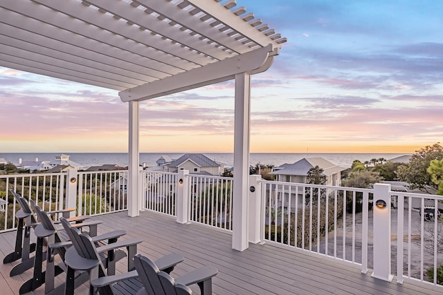 deck at dusk with a water view and a pergola