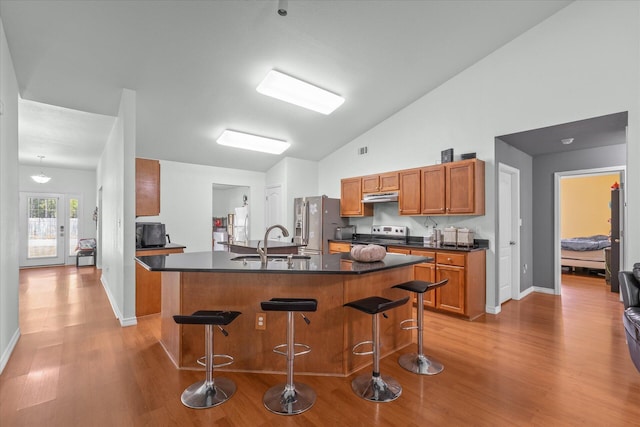 kitchen featuring light hardwood / wood-style floors, a kitchen island, sink, lofted ceiling, and a breakfast bar area