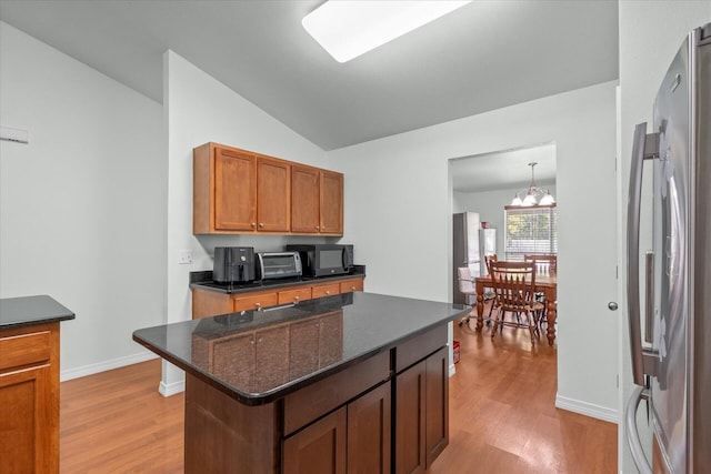 2458 Abaco Dr, Navarre, FL 32566 - kitchen with lofted ceiling, freestanding refrigerator, black microwave, a center island, and light wood-style flooring