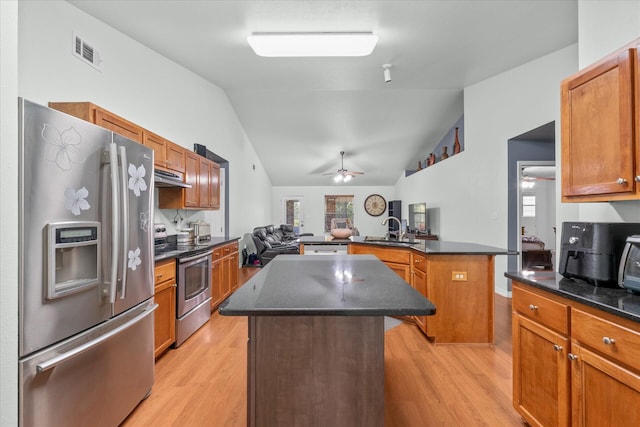 kitchen featuring appliances with stainless steel finishes, light hardwood / wood-style floors, lofted ceiling, a center island, and ceiling fan