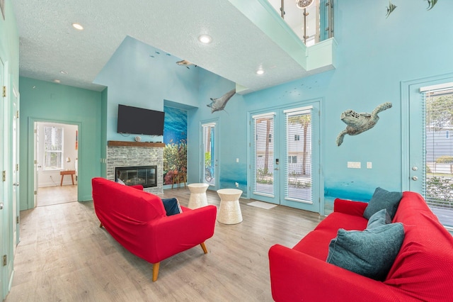 living room with a fireplace, a textured ceiling, plenty of natural light, and hardwood / wood-style floors