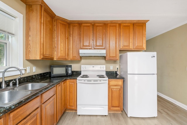 kitchen featuring sink, white appliances, light wood-type flooring, and dark stone counters