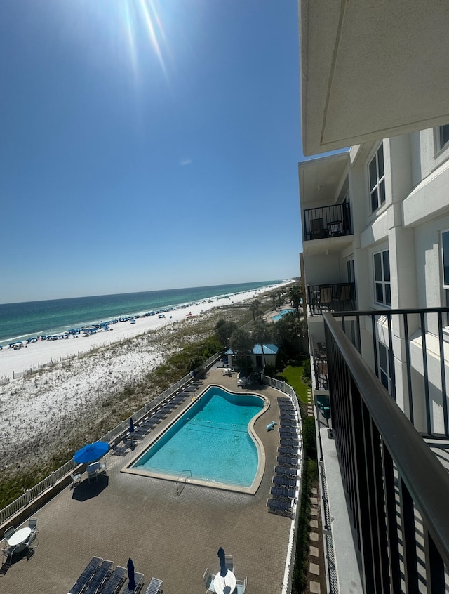 view of pool with a patio, a view of the beach, and a water view