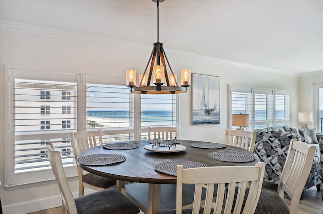 dining room with ornamental molding, a water view, an inviting chandelier, and wood-type flooring