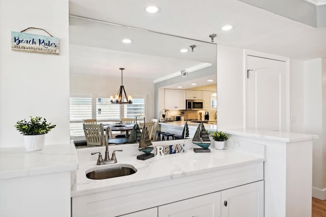 interior space with a notable chandelier, ornamental molding, hardwood / wood-style flooring, and vanity