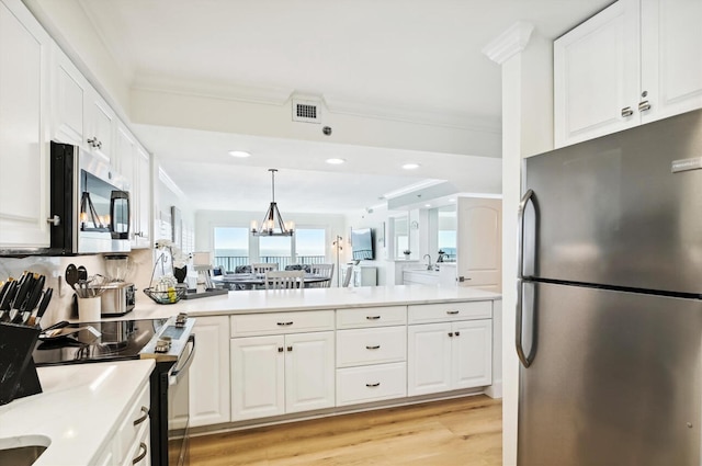 kitchen with stainless steel appliances, white cabinets, an inviting chandelier, and light wood-type flooring