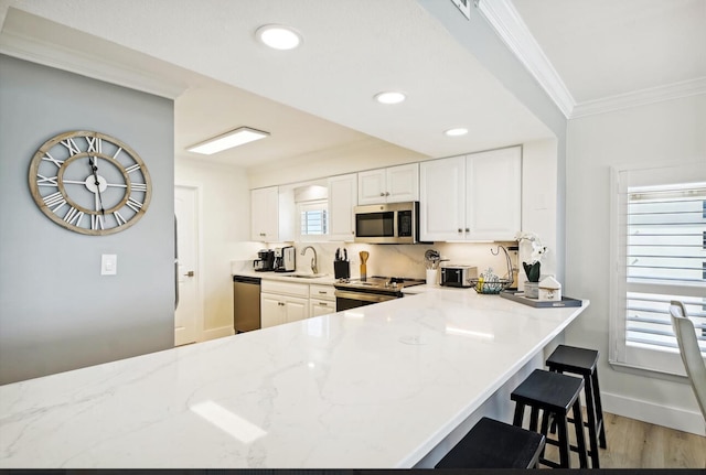 kitchen featuring stainless steel appliances, light hardwood / wood-style floors, crown molding, light stone countertops, and white cabinets